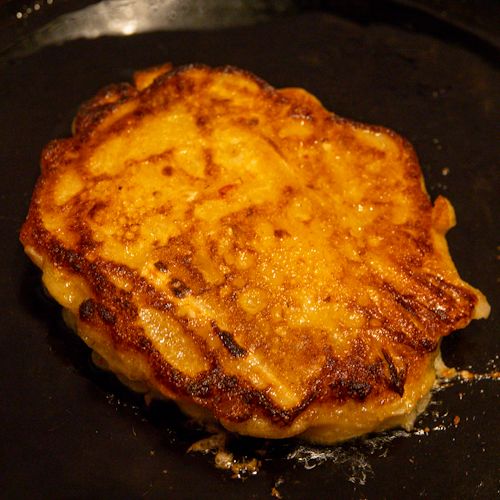 Kimchi pancakes being fried, after flipping.